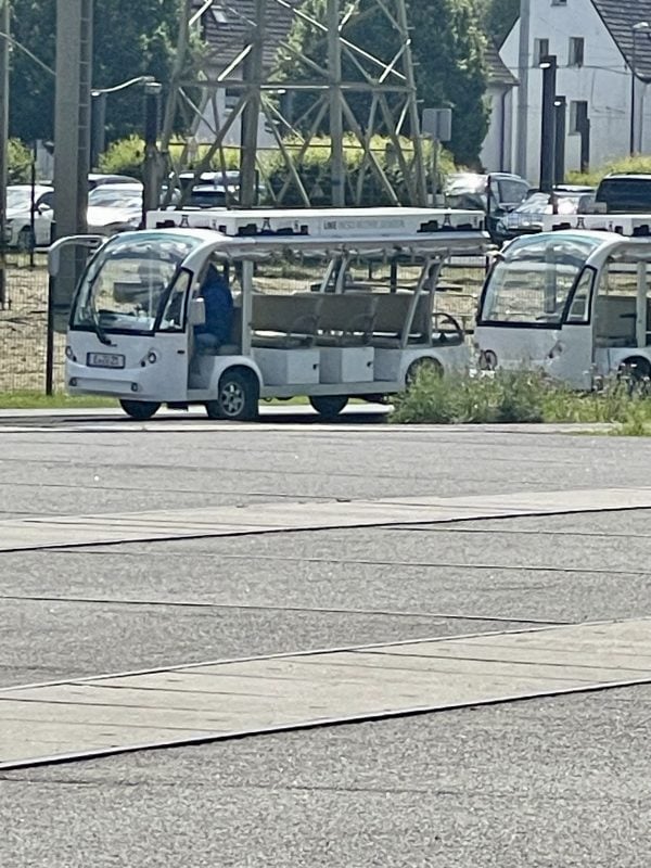 Two small buses are parked on the forecourt.