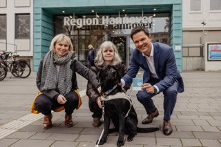 „Assistenzhund Willkommen“ – Regionspräsident Steffen Krach, Therese Fleßner mit ihrem Assistenzhund Folke (Foto, Mitte) und Sylvia Thiel, Beauftragte für Menschen mit Behinderungen der Region Hannover, beim Kampagnen-Auftakt vorm Regionshaus.